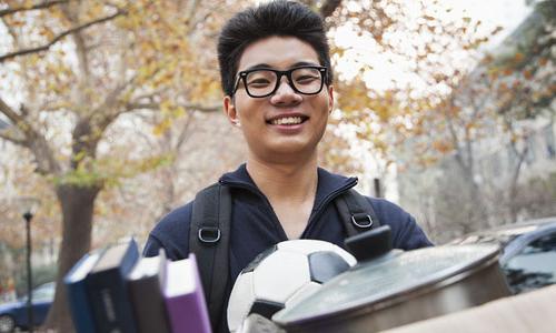 Student carrying a box of possessions as he moves into his dorm. 